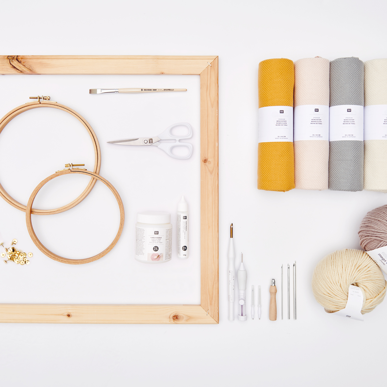 Punch Needle, Stickrahmen, Stoffrollen und Garn arrangiert auf grauem Hintergrund