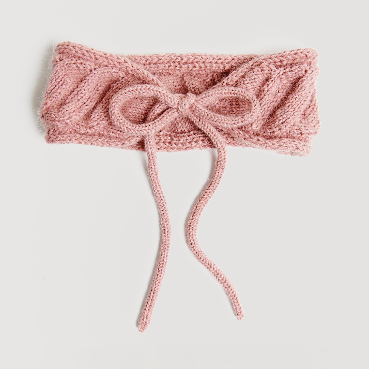 Die Neue Masche No. 13 Herbst von idee. Creativmarkt Strickset Stirnband Modell 12 in Perlrosa, gestrickt aus Essentials Merino dk Wolle. Elegantes Design mit Schleife, ideal für den Herbst.