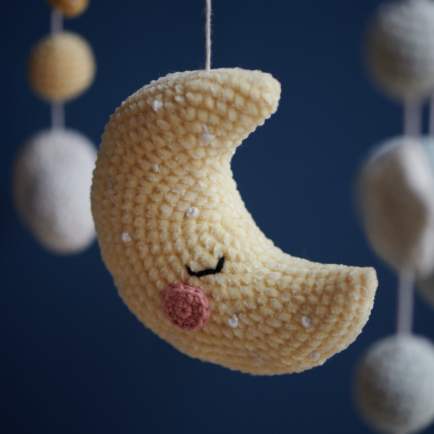 Ricorumi Glow In The Dark: Gelber gehäkelter Mondanhänger vor dunklem Hintergrund, ideal für Kinderzimmer.