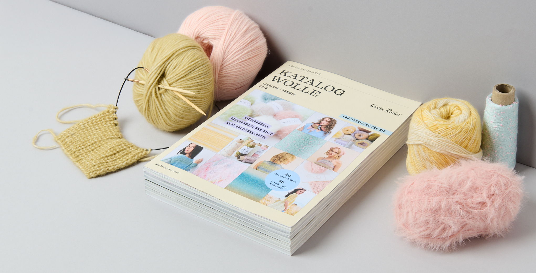Katalog Wolle liegt in grauer Ecke umgeben von Garnen