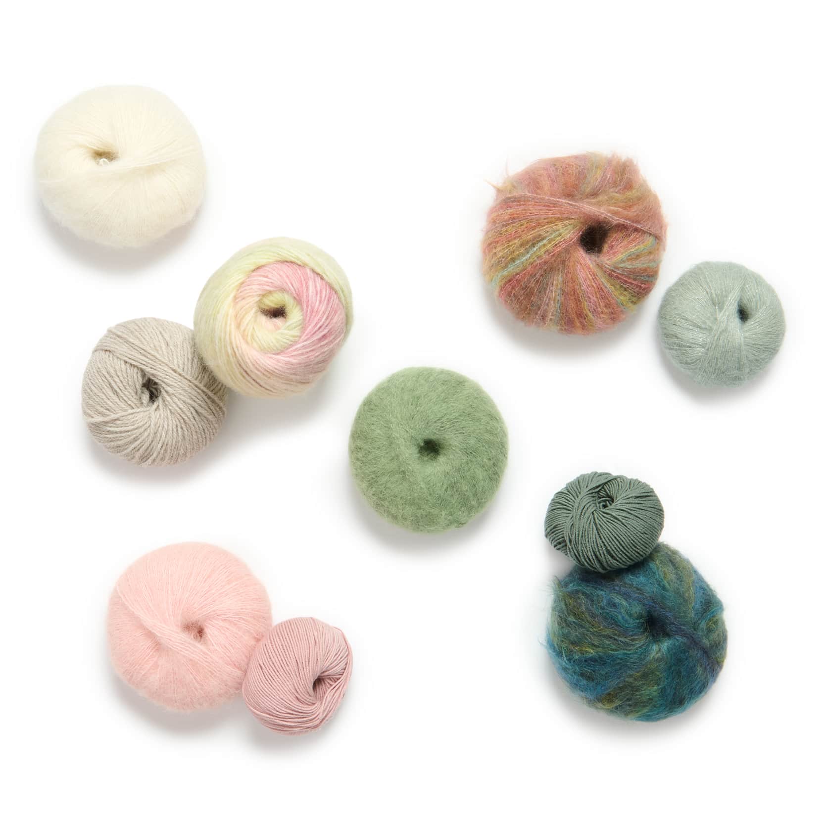 Verschiedene Garne in diversen Farben liegen verteilt auf weißem Hintergrund. Flatlay von Produkten.