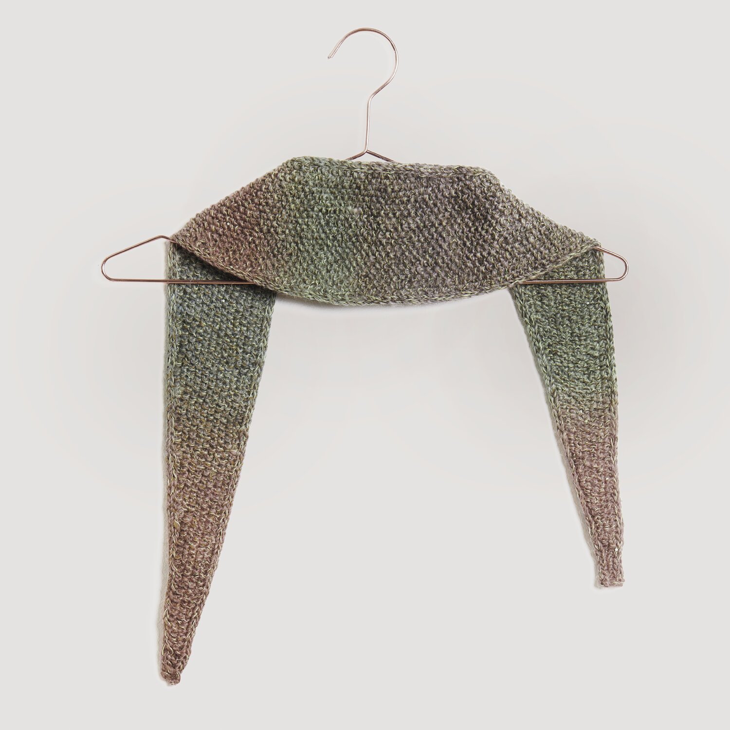 Lovewool No. 21 Herbst-Winter Sprachauswahl deutsch von Rico Design Brauner und grüner gestrickter Schal von Modell Legeware, drapiert auf einem Kleiderbügel. Der Schal zeigt ein dezentes Farbverlaufsmuster und ist ideal für kühle Tage.