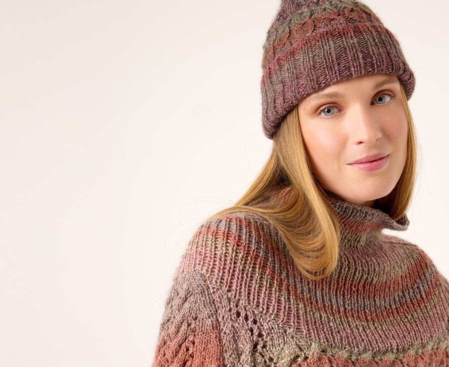 Frau trägt Strickmütze und Strickpullover vor einem neutralen Hintergrund