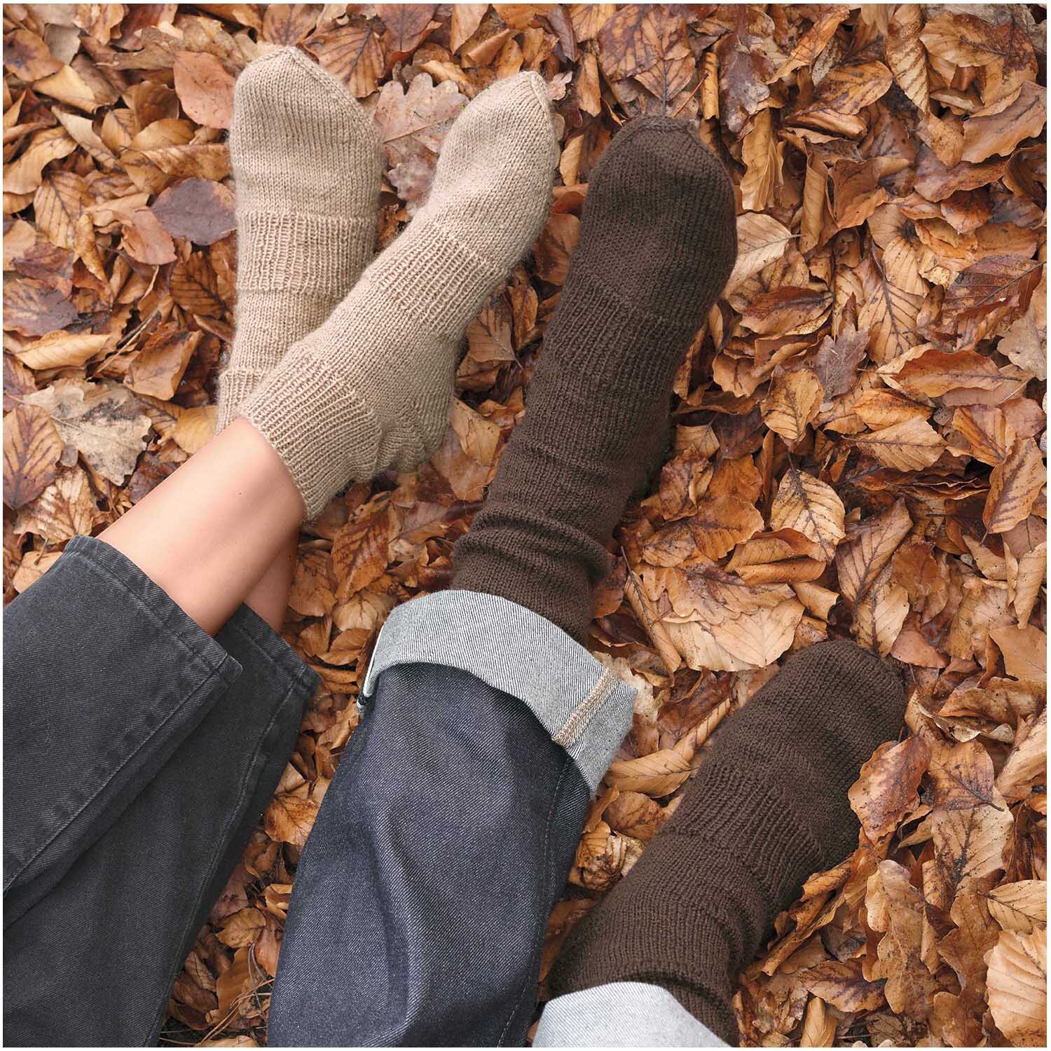 Essentials Fine Fine Merino Socken in Beige Melange und Dunkelbraun auf Herbstlaub liegend.