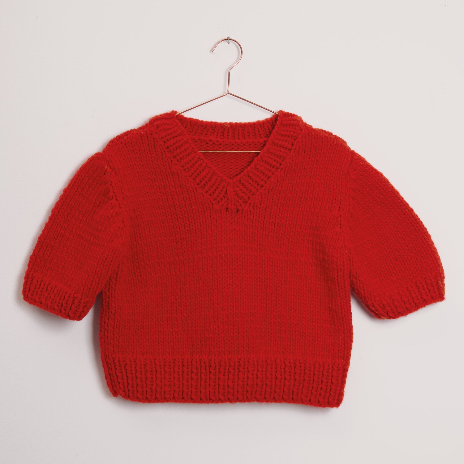 Essentials Super super chunky, Rico Design, kurzärmliger Strickpullover für Kinder in kräftigem Rot, präsentiert auf Bügel, Subtitel 100g 90m
