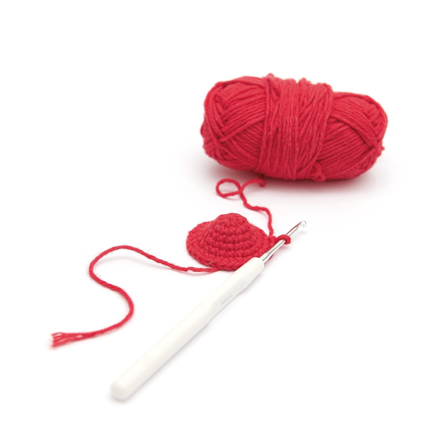 Ricorumi Adventskalender Weihnachtsmarkt: Rotes Garnknäuel mit Häkelnadel und begonnenem Häkelstück. Ideal für kreative Projekte.