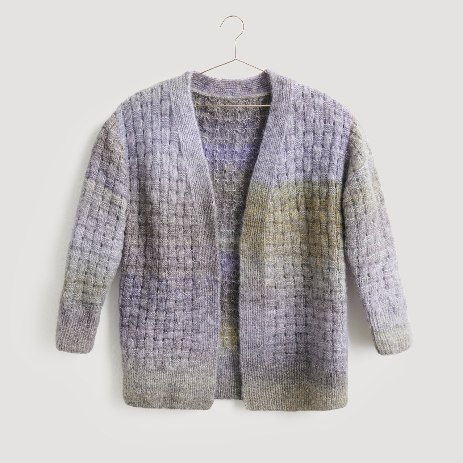 Lovewool No. 21 Herbst-Winter Sprachauswahl deutsch von Rico Design Strickjacke in sanften Lila- und Grautönen, aufgehängt an einem Kleiderbügel. Marke: Modell Legeware. Ideal für kühle Tage, bietet Komfort und Stil. Perfekt für den lässigen Look.