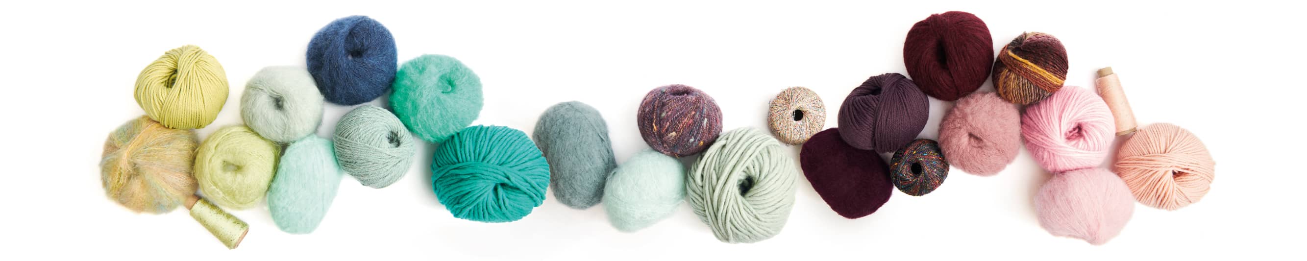 Wollknäuel in verschiedenen Farben aneinandergereiht 