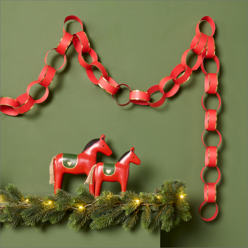 Papiergirlande und Weihnachtsdekoration mit roten Holzpferden.