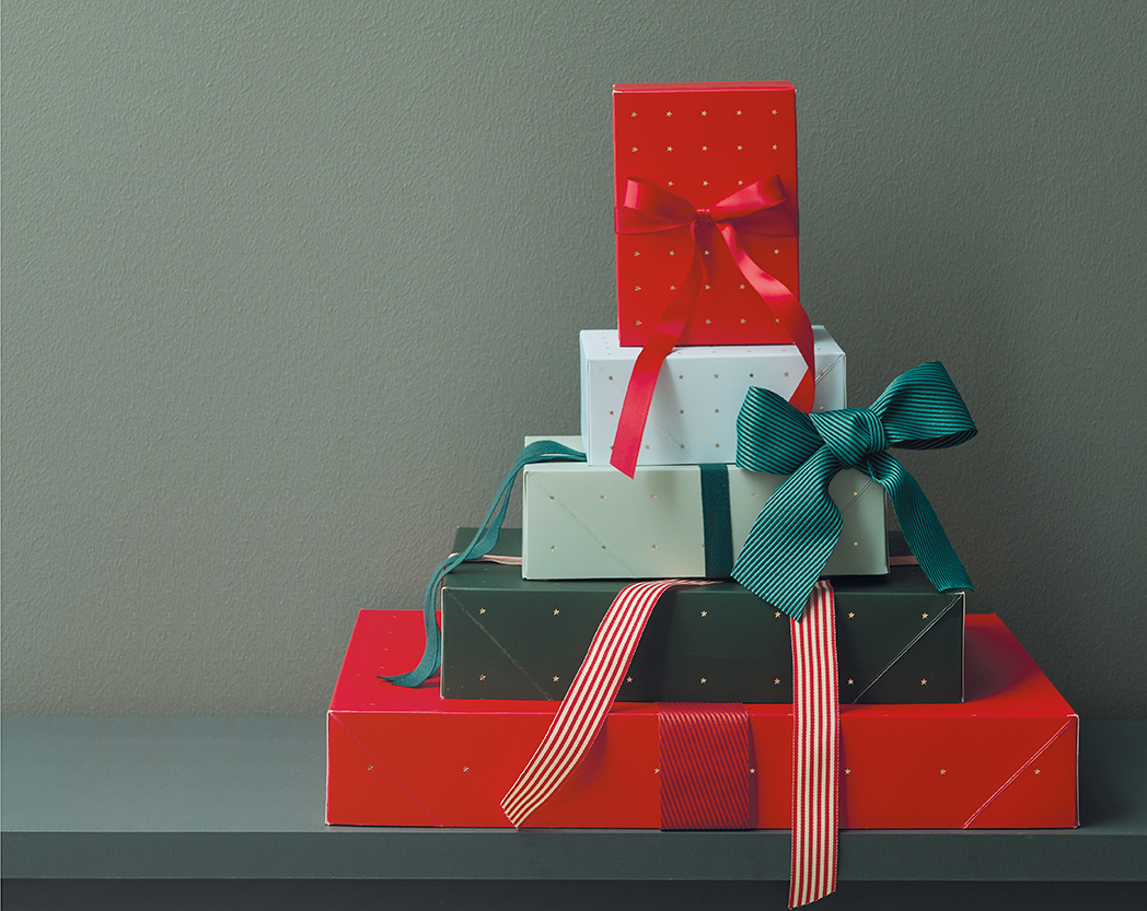 Fünf Geschenke, in roten und grünen Farben und mit Schleifen verpackt, sind der Größe nach übereinandergestapelt. Fotosetting grüner Hintergrund.