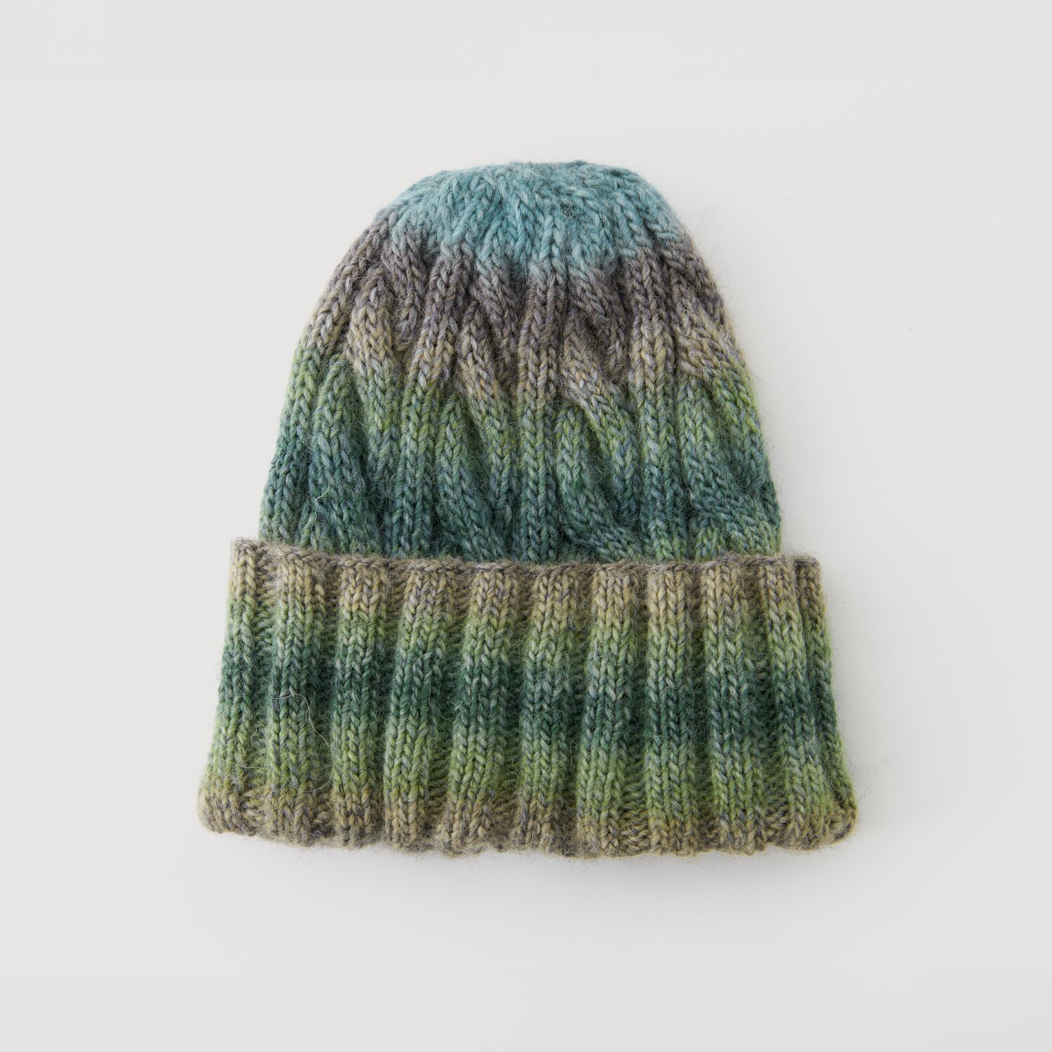 Lovewool No. 21 Herbst-Winter Sprachauswahl deutsch von Rico Design Strickmütze in Blau- und Grüntönen, Modell Legeware. Die Mütze zeigt ein Zopfmuster und ist ideal für kalte Tage. Perfekt für stilvolle Wintermode.