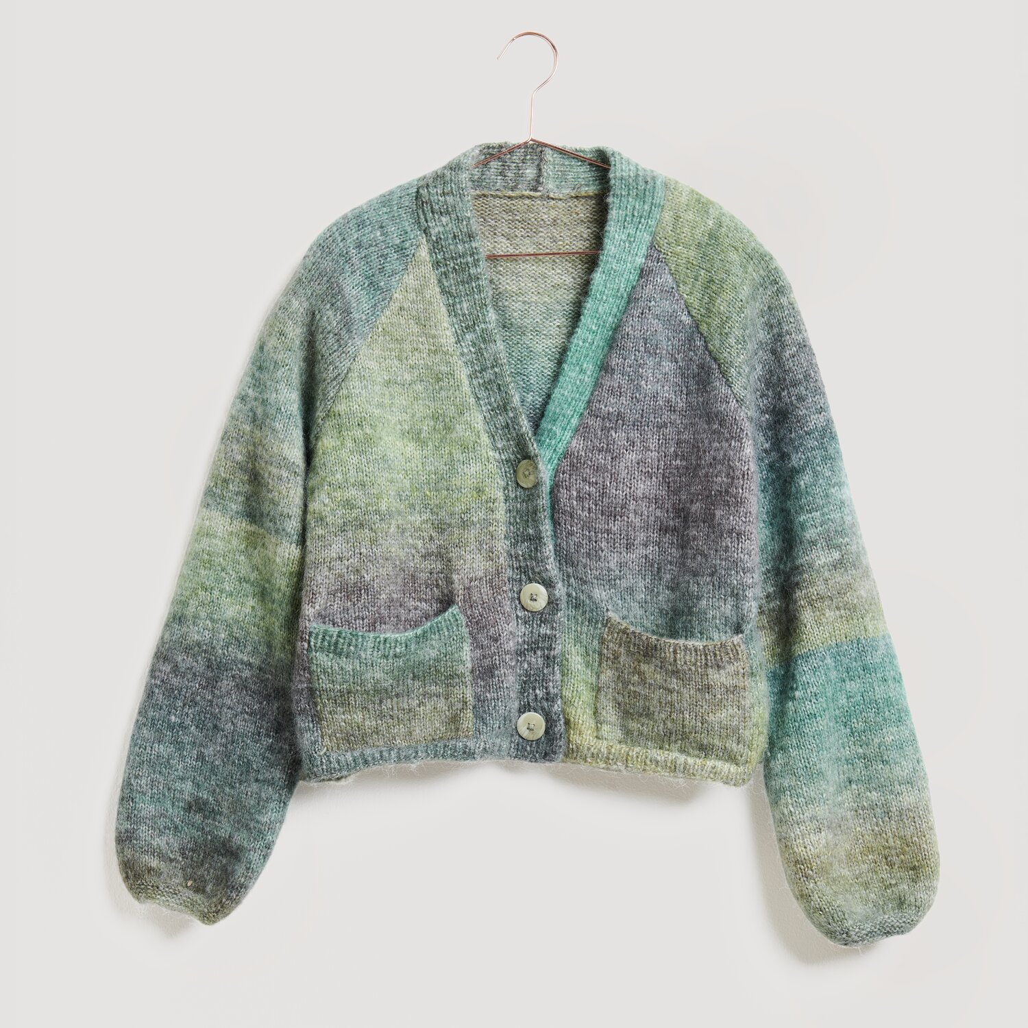 Lovewool No. 21 Herbst-Winter Sprachauswahl deutsch von Rico Design Strickjacke in sanften Blau- und Grüntönen, Modell Legeware. Die Jacke hat einen V-Ausschnitt, Knöpfe und zwei Taschen. Perfekt für einen gemütlichen, stilvollen Look.