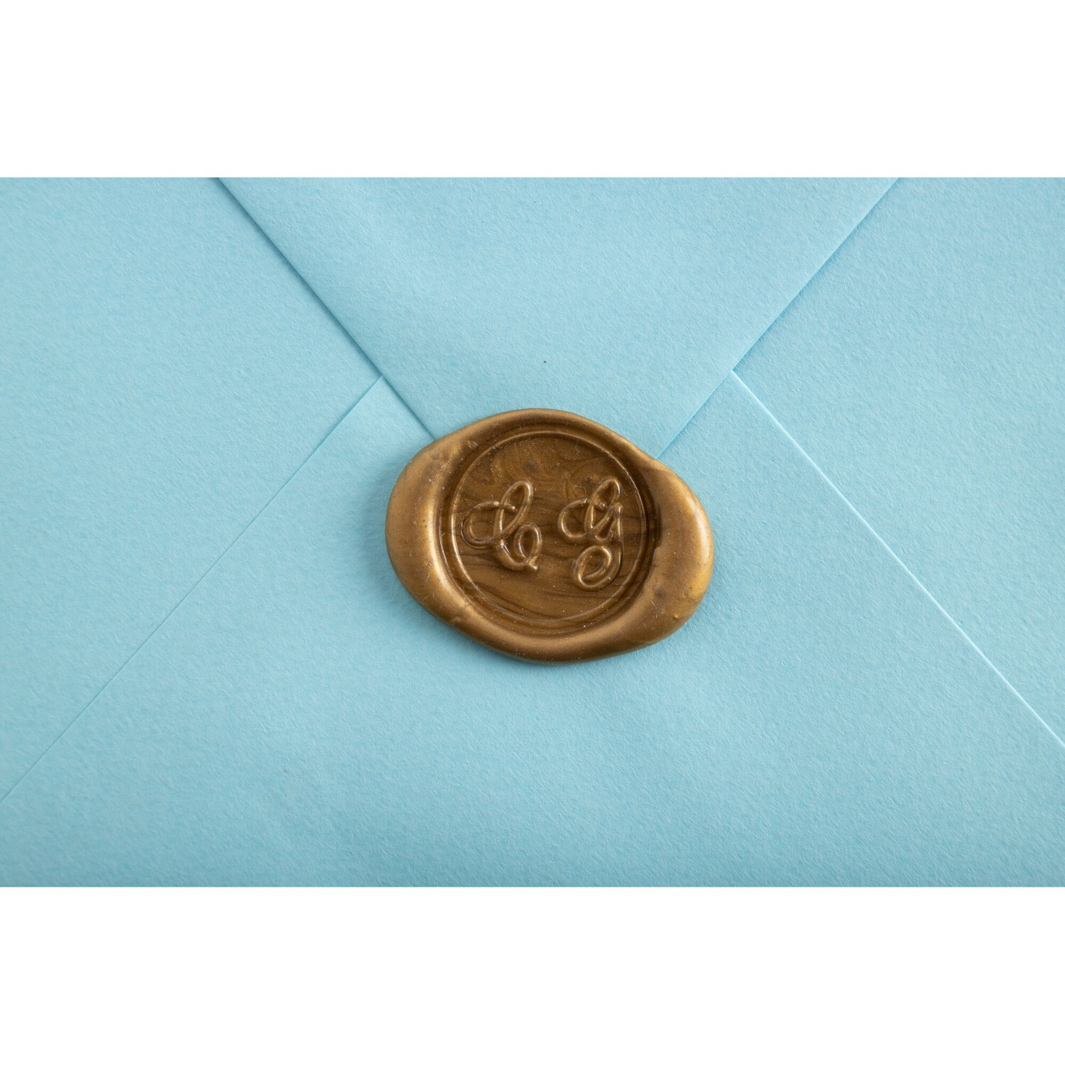 Siegelwachs Stangen, 6-teilig: Goldener Wachssiegel auf hellblauem Umschlag für elegante Post.