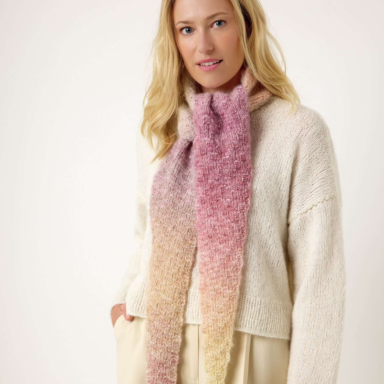 Strickset Dreieckstuch Modell 06 aus Die Neue Masche No. 13 von idee. Creativmarkt Strickset Dreieckstuch Modell 06: Frau trägt pastellfarbenes Tuch und cremefarbenen Pullover.