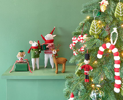 Zwei Filzmäuse, ein Filzhirsch und ein Filzengel, sowie Weihnachtsbaumornamente aus Filz. Fotosetting grünes Regal und Tannenbaum.