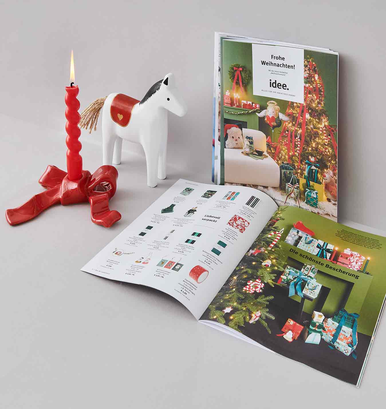 Prospekt Titel und aufgeschlagen, Kerzen und Holzpferd stehen daneben