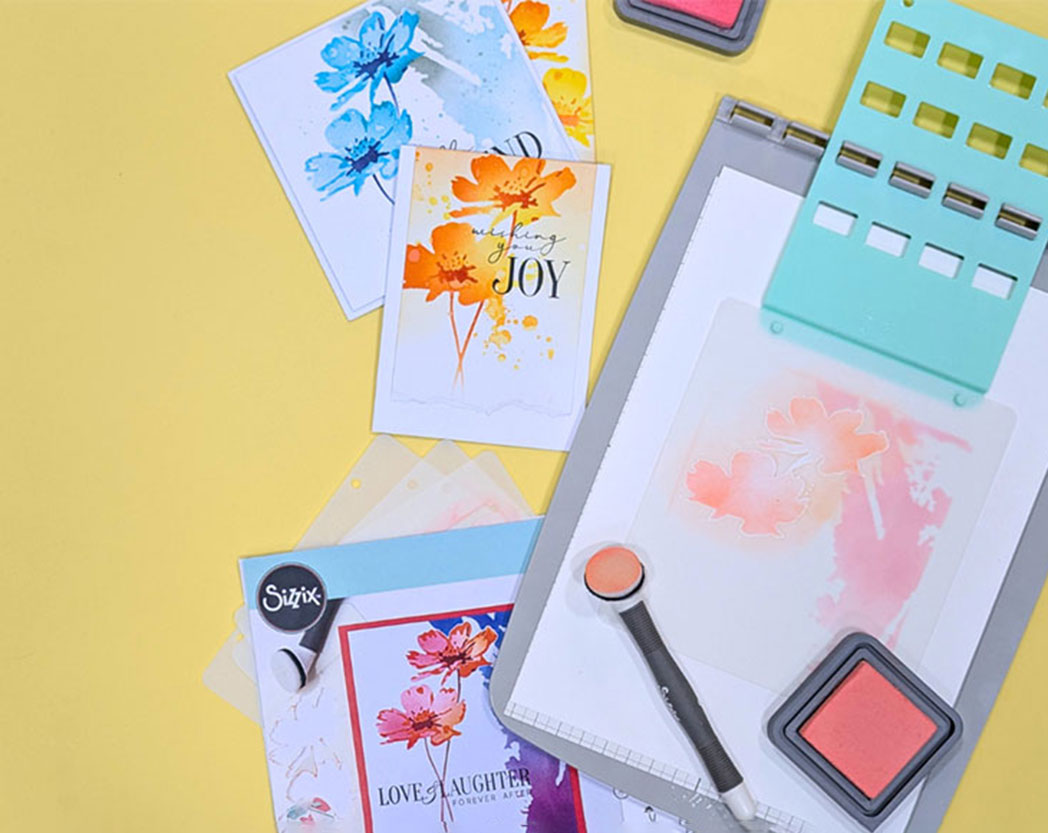 Gestaltete Karten mit Blumendesign und Schriftzug, daneben ein Schablonen-Tool mit Pinsel und Farbe. Flatlay von Produkten.