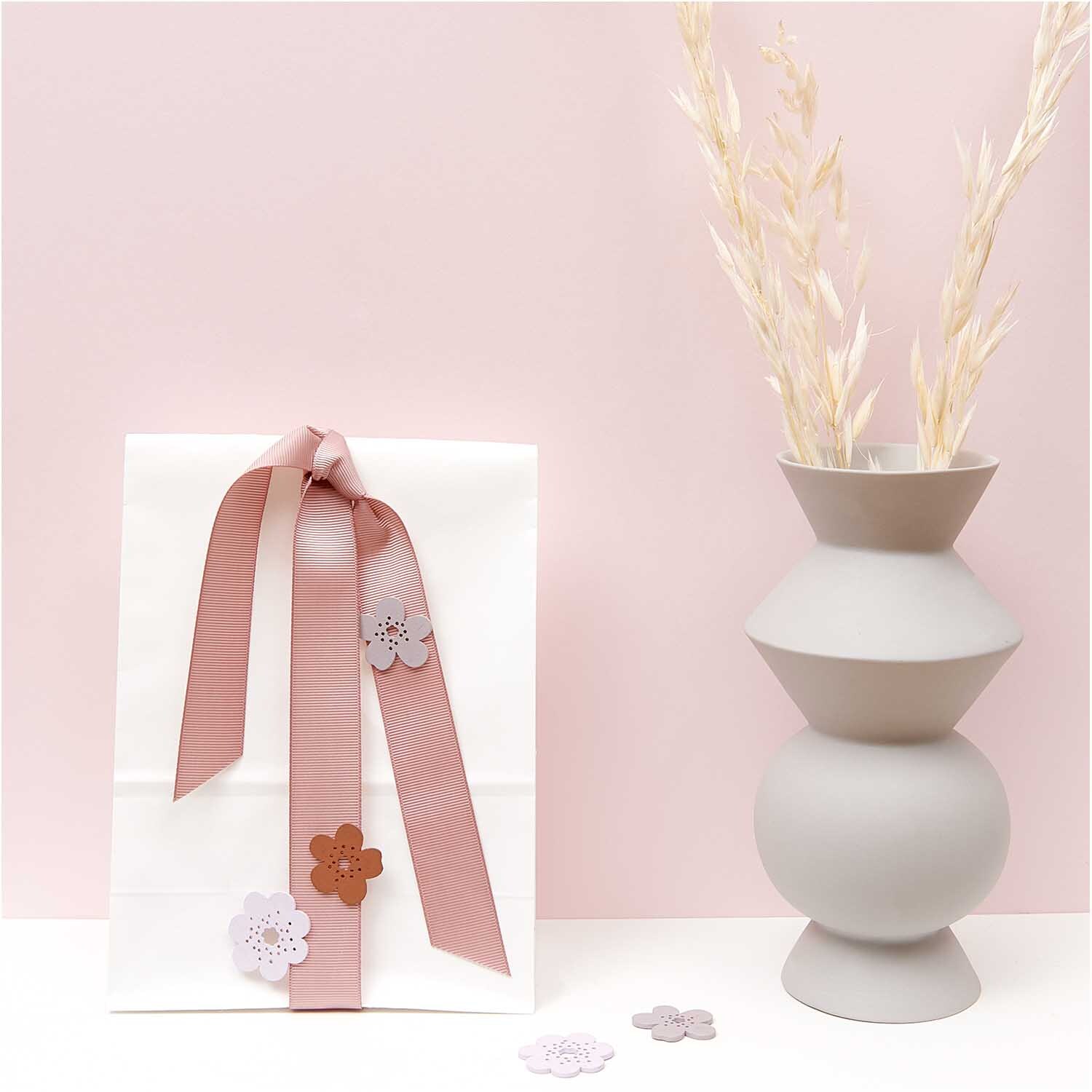 Holzstreu Blüte Mix 12 Stück: Dekorative Blumen in Mauve auf Geschenk mit Schleife, neben grauer Vase.