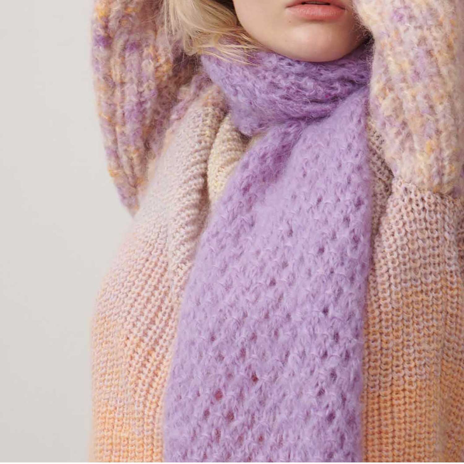 Fashion Mohair Merino Chunky 50g 100m Farbe Flieder von Rico Design Fashion Mohair Merino Chunky: Frau trägt fliederfarbenen Schal und Pullover aus weichem Strick von Rico Design.