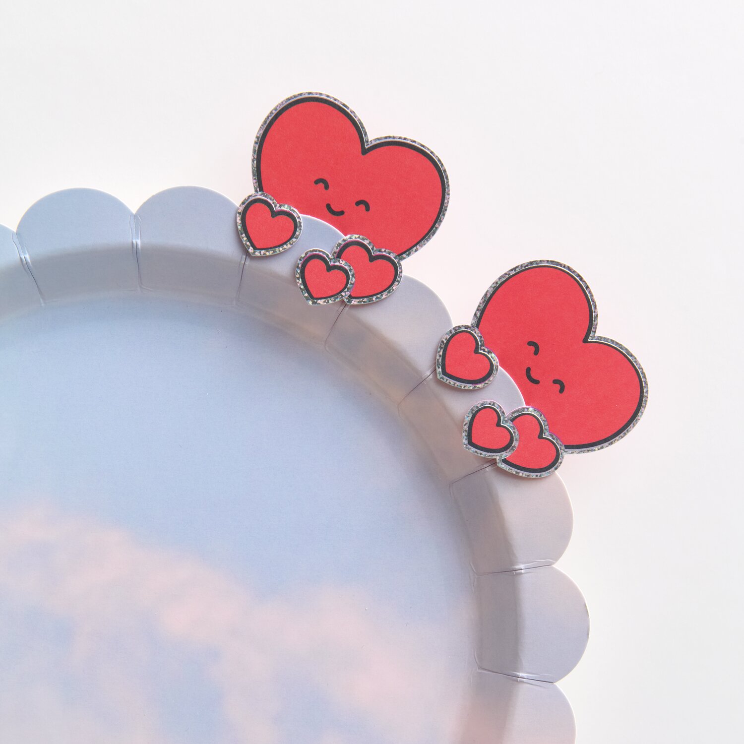 Paper Poetry Clip-Ons Chingu Herzen Rot: Zwei rote Herz-Clips auf einem grauen Teller, 8-teilig.