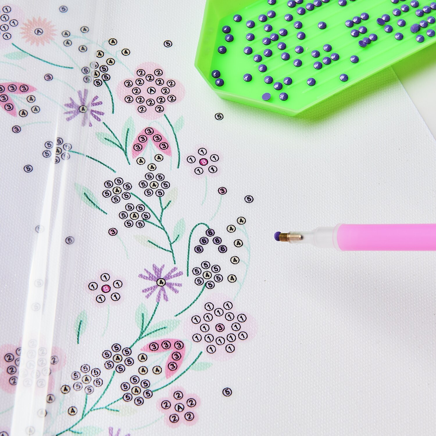 Diamond Painting DIY-Set Funkelnder Blumenkranz: Nahaufnahme eines floralen Designs mit rosa Stift und grüner Perlenablage. Ø20cm.