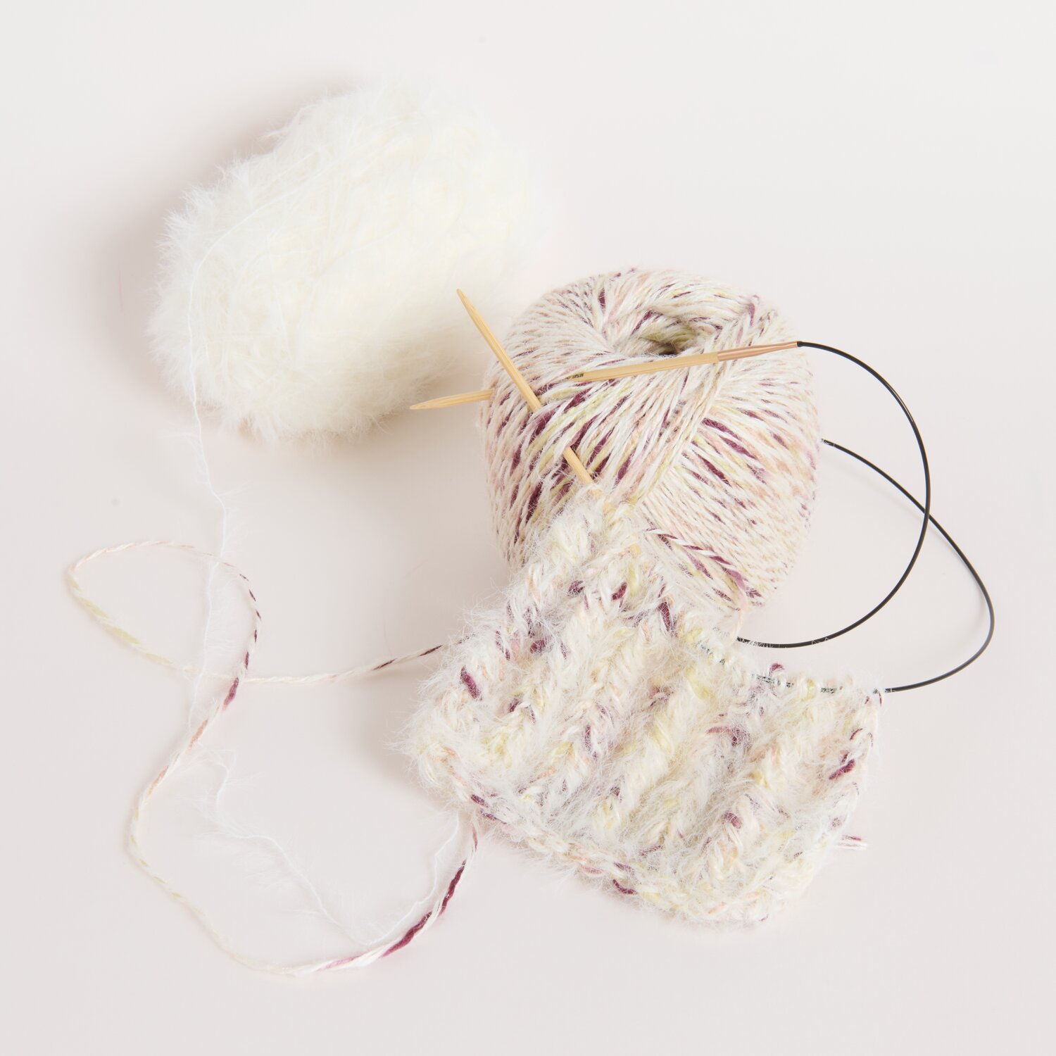 Berries Weiß: Strickprojekt mit weißem Garn und Nadeln auf hellem Hintergrund, Rico Design.