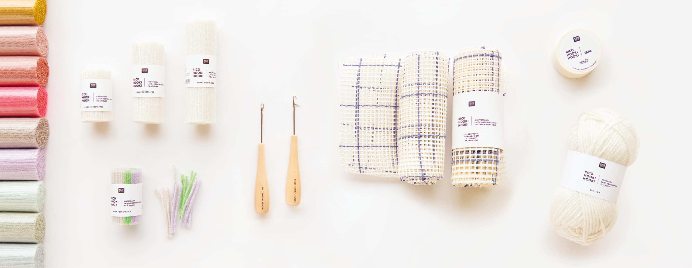 Knüpfgarn in diversen Farben liegen mit Knüpfhaken, Stramin und Knüpfmaterial auf weißem Hintergrund