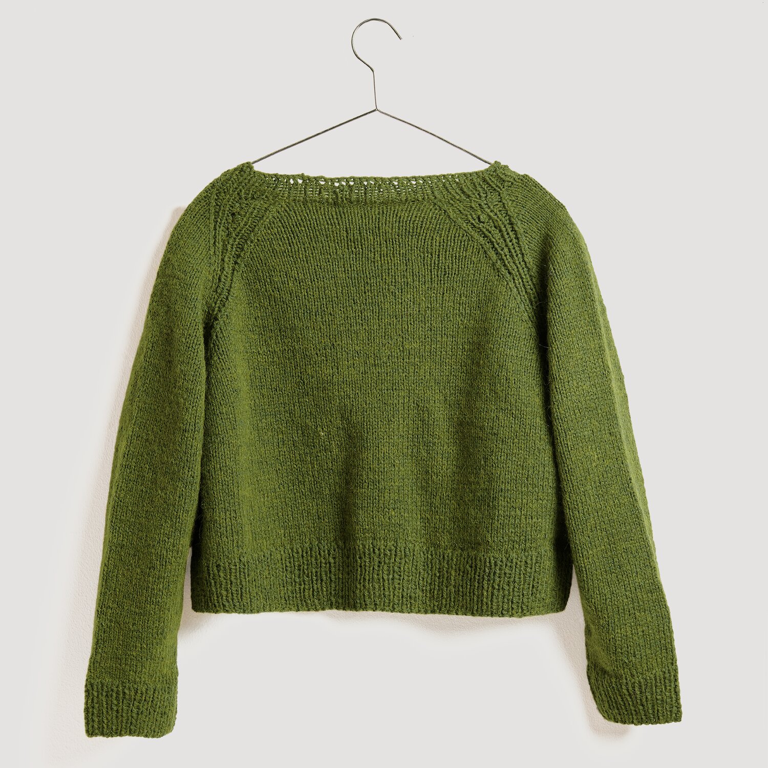 Die Neue Masche No. 13 Herbst von idee. Creativmarkt Soft Alpaca Pullover in Oliv, gestrickt aus Rico Design Wolle, präsentiert auf einem Kleiderbügel.