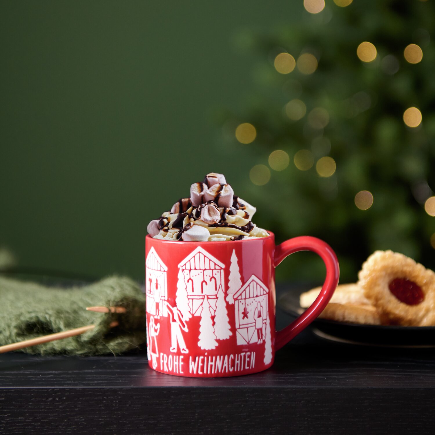 Porzellan Tasse Weihnachtsmarkt mit heißer Schokolade, dekoriert mit Sahne und Keksen, vor einem Weihnachtsbaum.