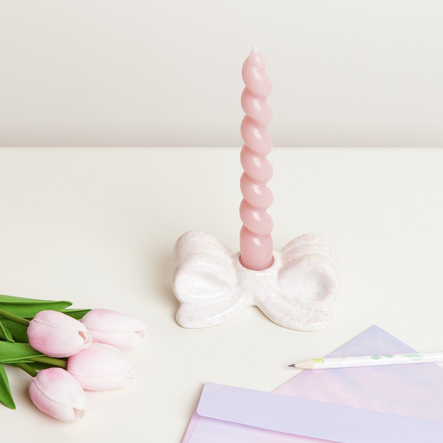 Kerzenhalter Schleife Konfetti: Weißer Halter von Rico Design mit rosa Kerze, umgeben von Tulpen.