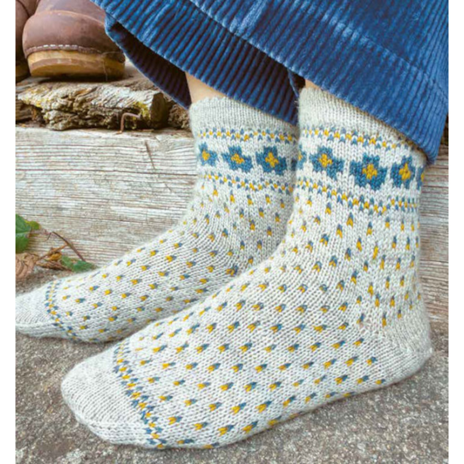 Einzigartige Motivsocken stricken: Handgestrickte Socken mit blau-gelbem Muster auf grauem Hintergrund. Ideal für gemütliche Tage.