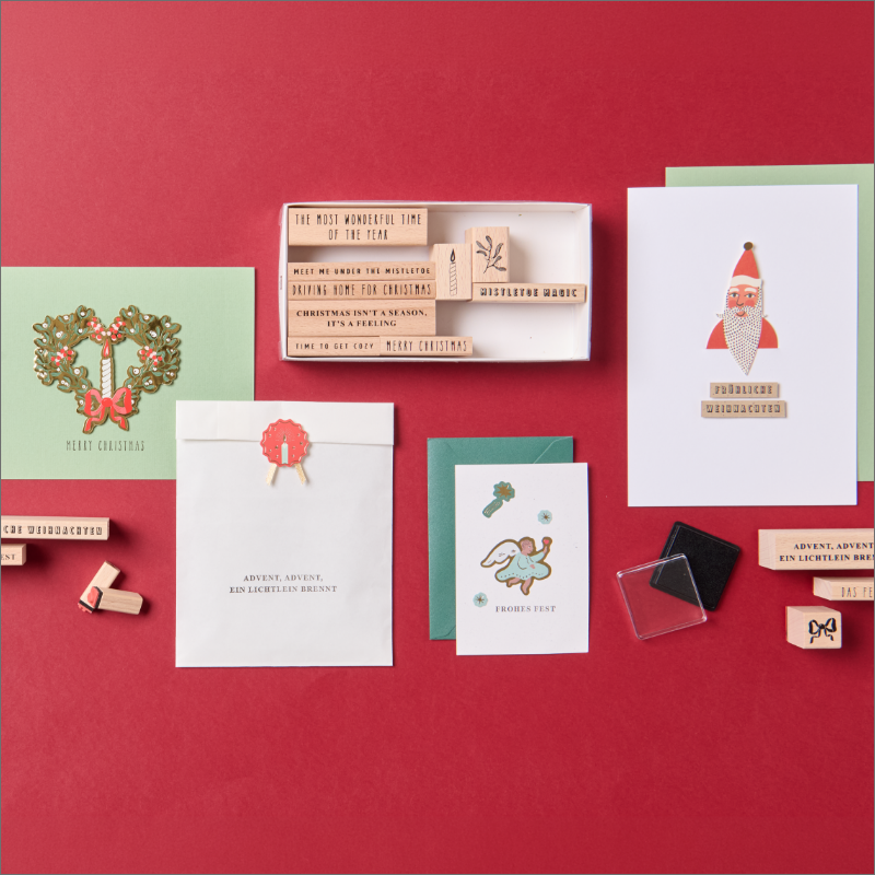 Selbst gestaltete Weihnachtskarten und Geschenkverpackungen mit Stempeln vor rotem hintergrund.