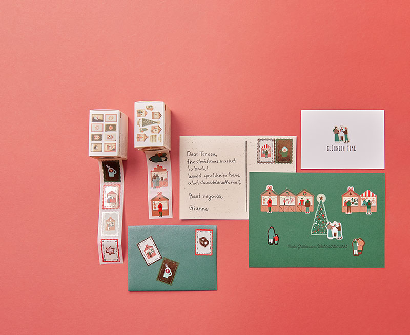 Verschiedene Karten und Umschläge mit weihnachtlichen Stickern verziert, sowie zwei Sticker-Verpackungen. Flatlay von Produkten.