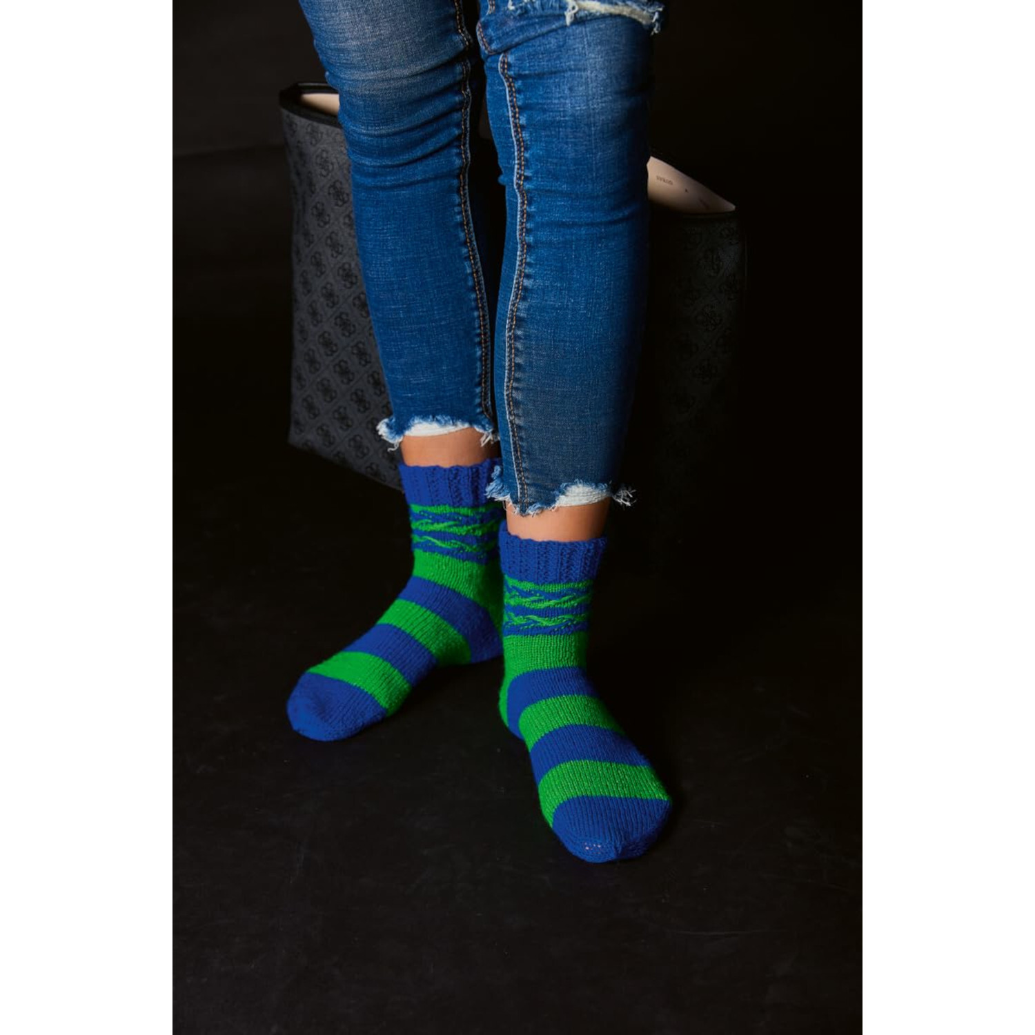 Socken stricken mit Wow-Effekt: Person trägt blau-grün gestreifte Socken und zerrissene Jeans.