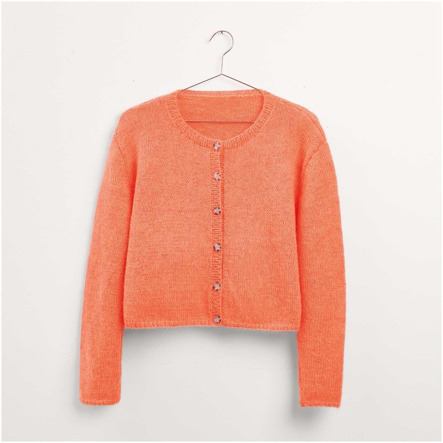 Strickset Jacke Modell 24 aus Made by Me Nr. 17 in leuchtendem Orange. Die Jacke ist auf einem Kleiderbügel präsentiert und zeigt ein schlichtes, elegantes Design mit Knopfleiste. Ideal für modische Strickliebhaber.