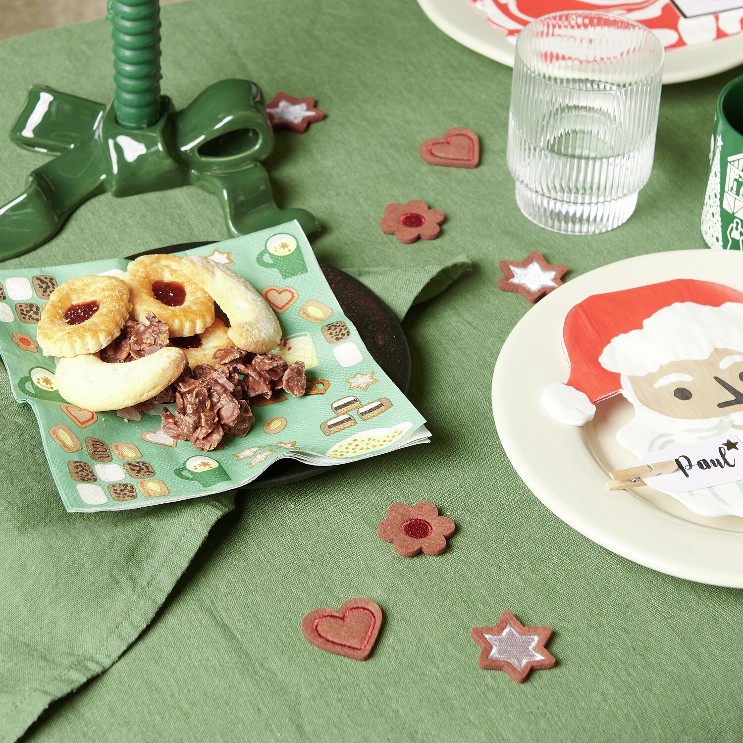 Filzstreu Gebäck auf grünem Tisch mit Weihnachtsdekoration, Teller und Glas, 6 Stück.