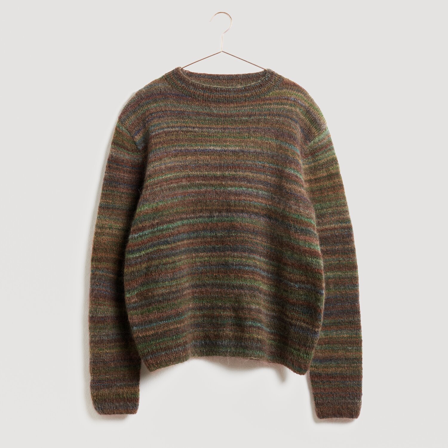 Lovewool No. 21 Herbst-Winter Sprachauswahl deutsch von Rico Design Brauner, gestreifter Pullover von Modell Legeware, hängend an einem Kleiderbügel. Der Pullover zeigt ein dezentes, mehrfarbiges Streifenmuster und ist ideal für kühle Tage.