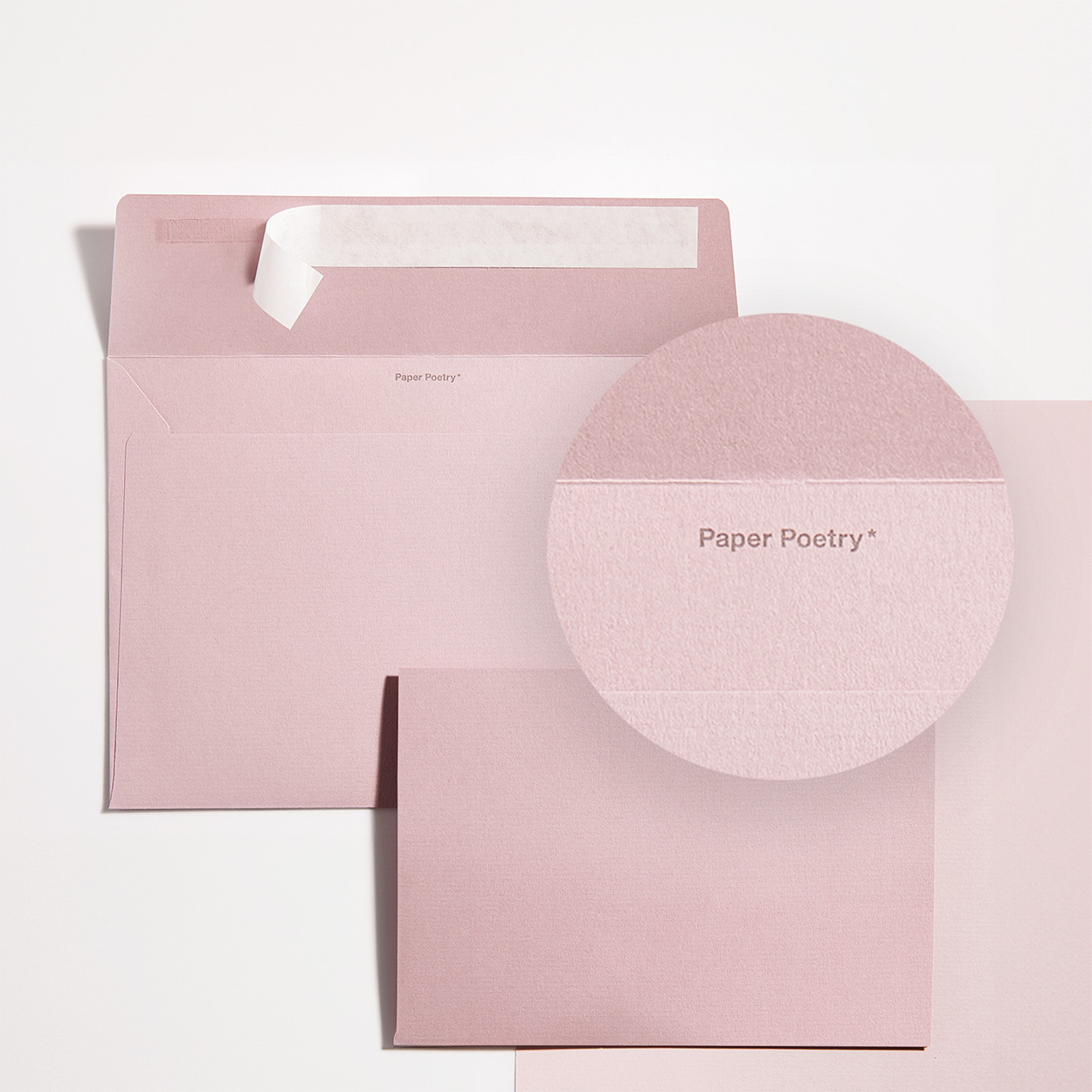 Rosa Umschlag mit passender Karte und Close-Up von Schriftzug im Umschlag. Flatlay von Produkten.