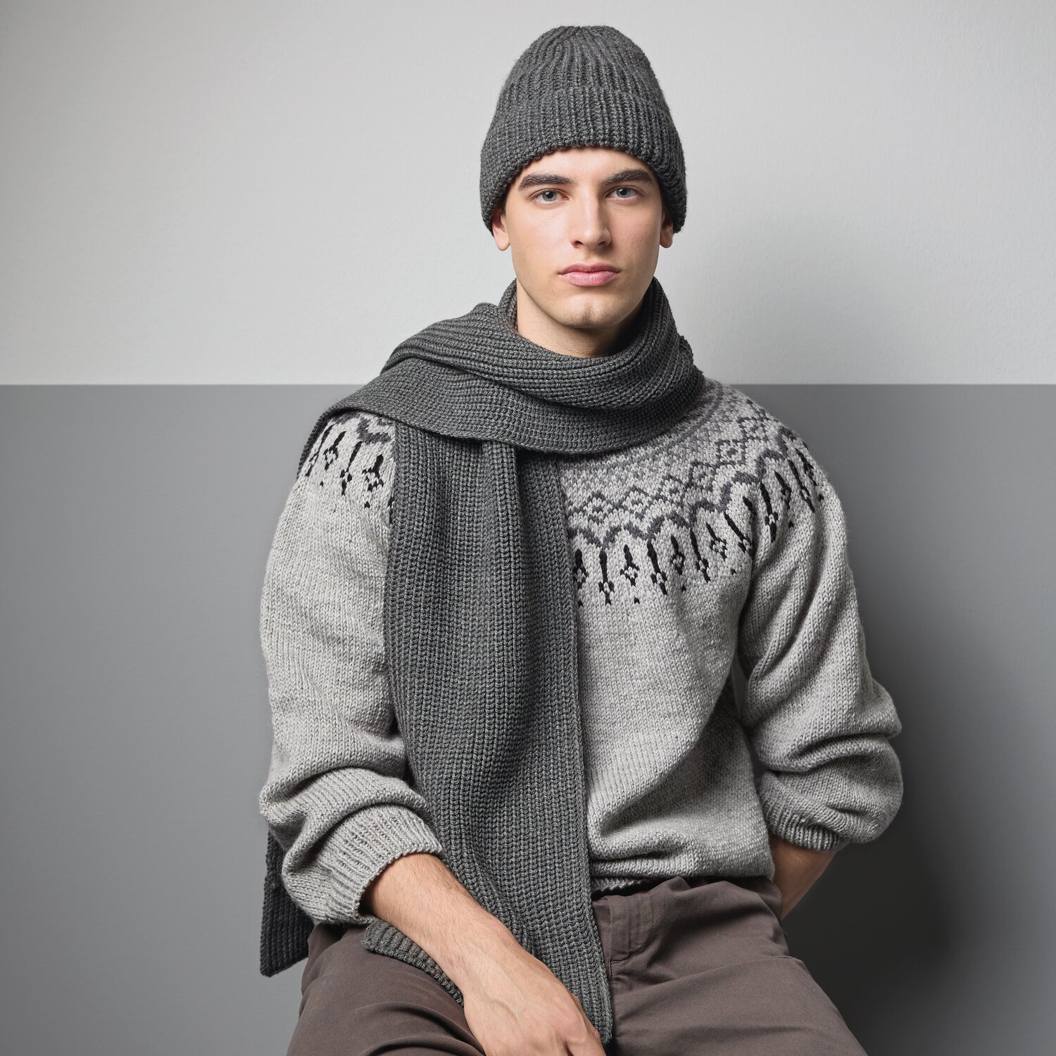Strickset Mütze Modell 05 aus Made by Me Men No. 3: Mann trägt graue Mütze und Schal, kombiniert mit gestricktem Pullover in modernem Design.