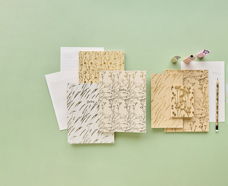 Notizbücher in verschiedenen Größen, Motiven und ein Bleistift mit drei Radiergummis. Flatlay von Produkten aus der Kollektion In The Meadow.