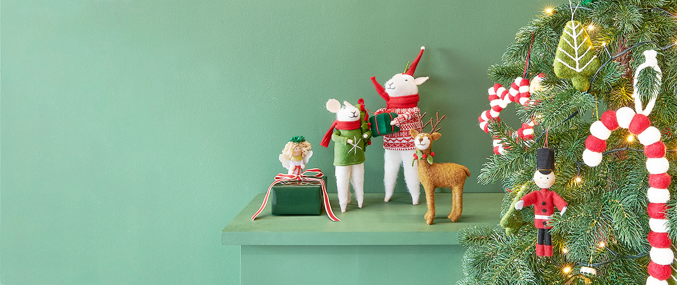 Zwei Filzmäuse, ein Filzhirsch und ein Filzengel, sowie Weihnachtsbaumornamente aus Filz. Fotosetting grünes Regal und Tannenbaum.