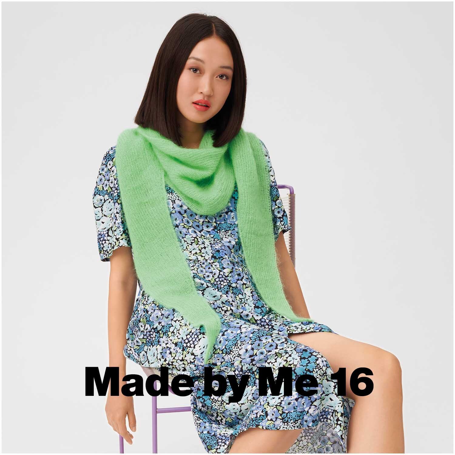 Essentials Super Kid Mohair Loves Silk: Frau trägt neongrünen Schal von Rico Design, kombiniert mit geblümtem Kleid, sitzt auf Stuhl.