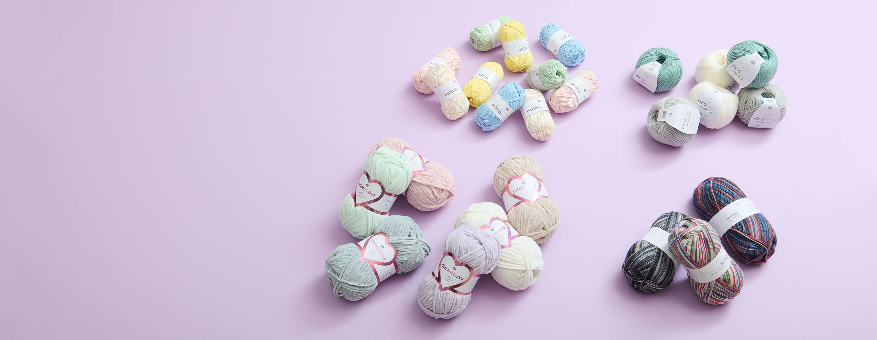 Unterschiedliche Wolle zusammenliegend auf kleinen Haufen und lila Hintergrund. Flatlay von Produkten.