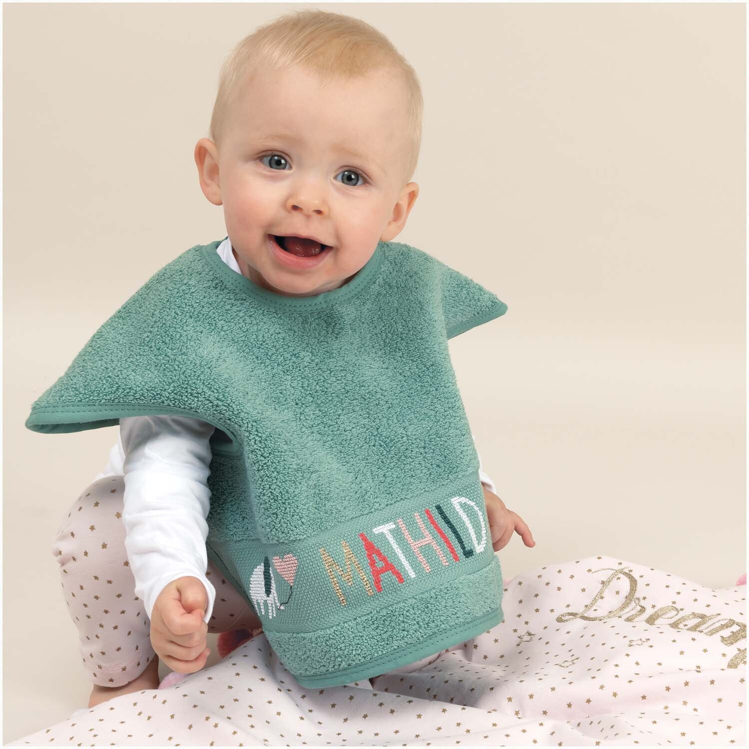 Ärmellätzchen 40x49cm in Meergrün von Rico Design, getragen von einem lächelnden Baby auf einer Decke.