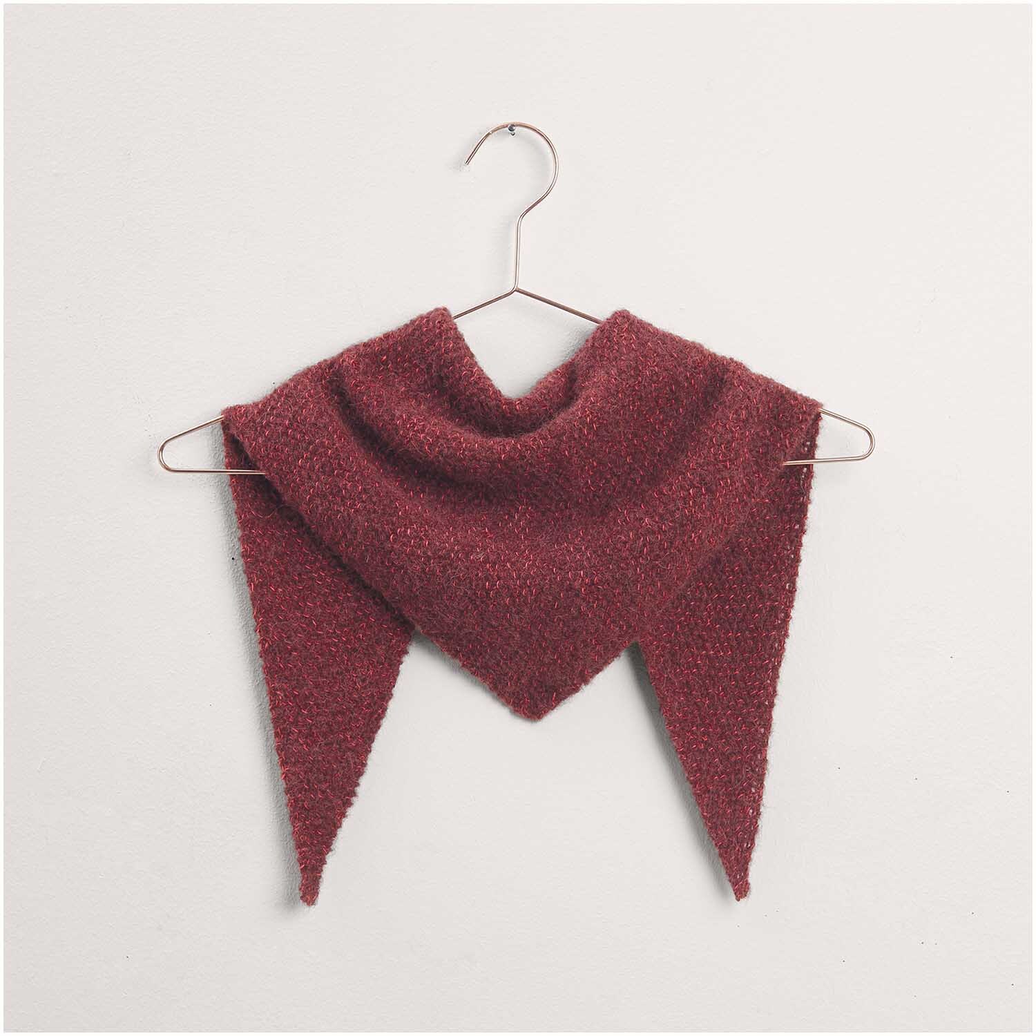 Dreieckstuch in Bordeauxrot, präsentiert auf einem Kleiderbügel. Strickset von "Made by Me", Modell 38 aus der Kollektion Nr. 17. Perfekt für stilvolle, handgemachte Mode.