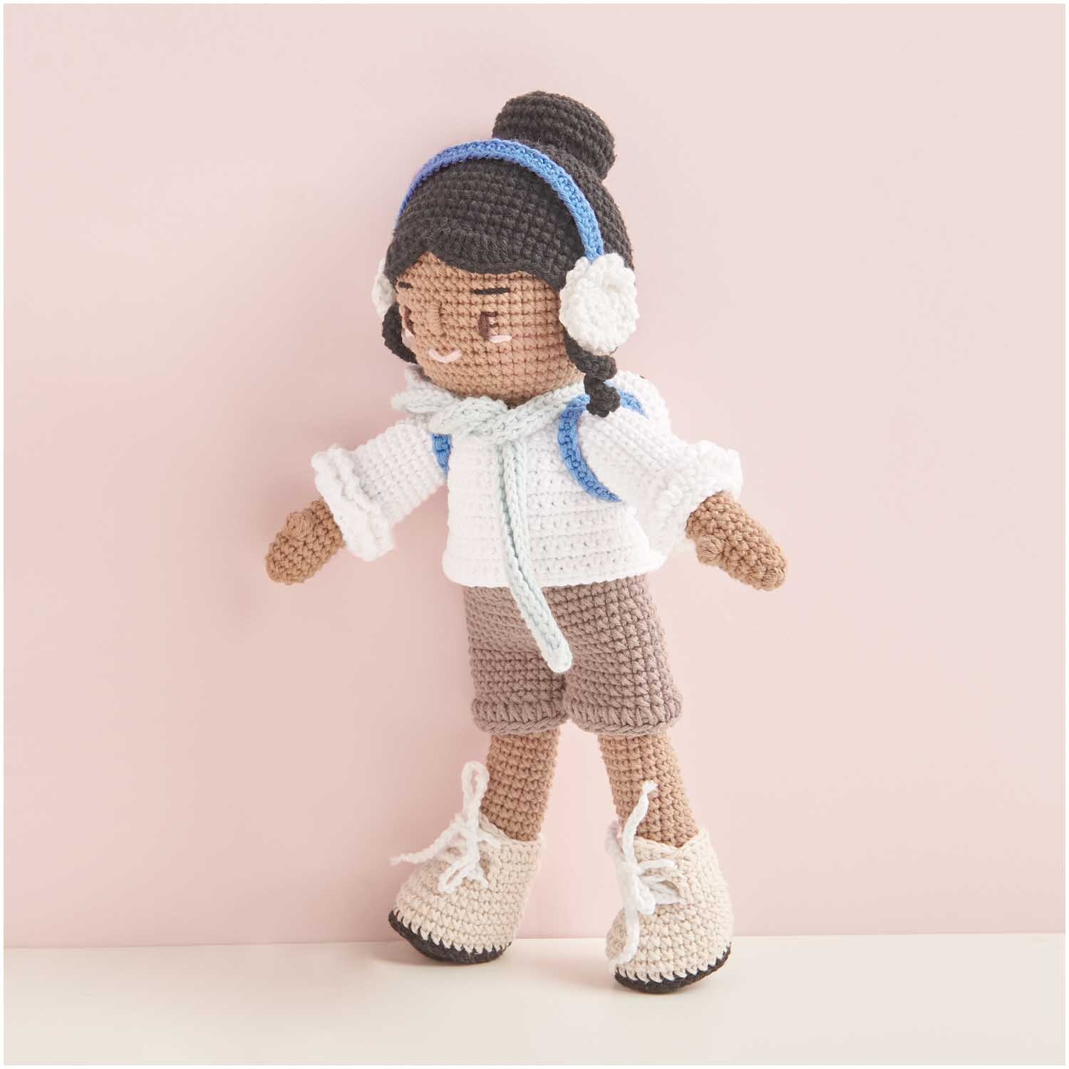 Creative Ricorumi dk: Gehäkelte Puppe mit weißem Pullover, blauen Kopfhörern und beigen Stiefeln.