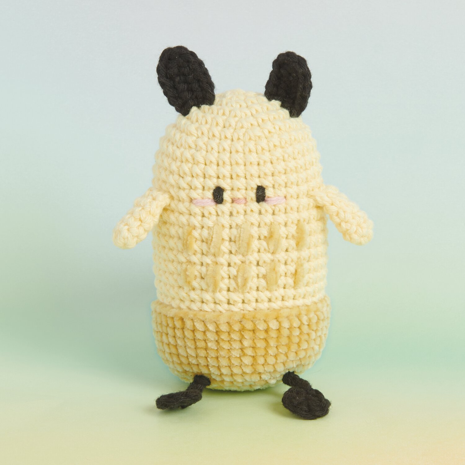 Ricorumi Rainbow Weirdos, gehäkelte Figur in Vanille und Senf mit schwarzen Details. Ideal für kreative Projekte.