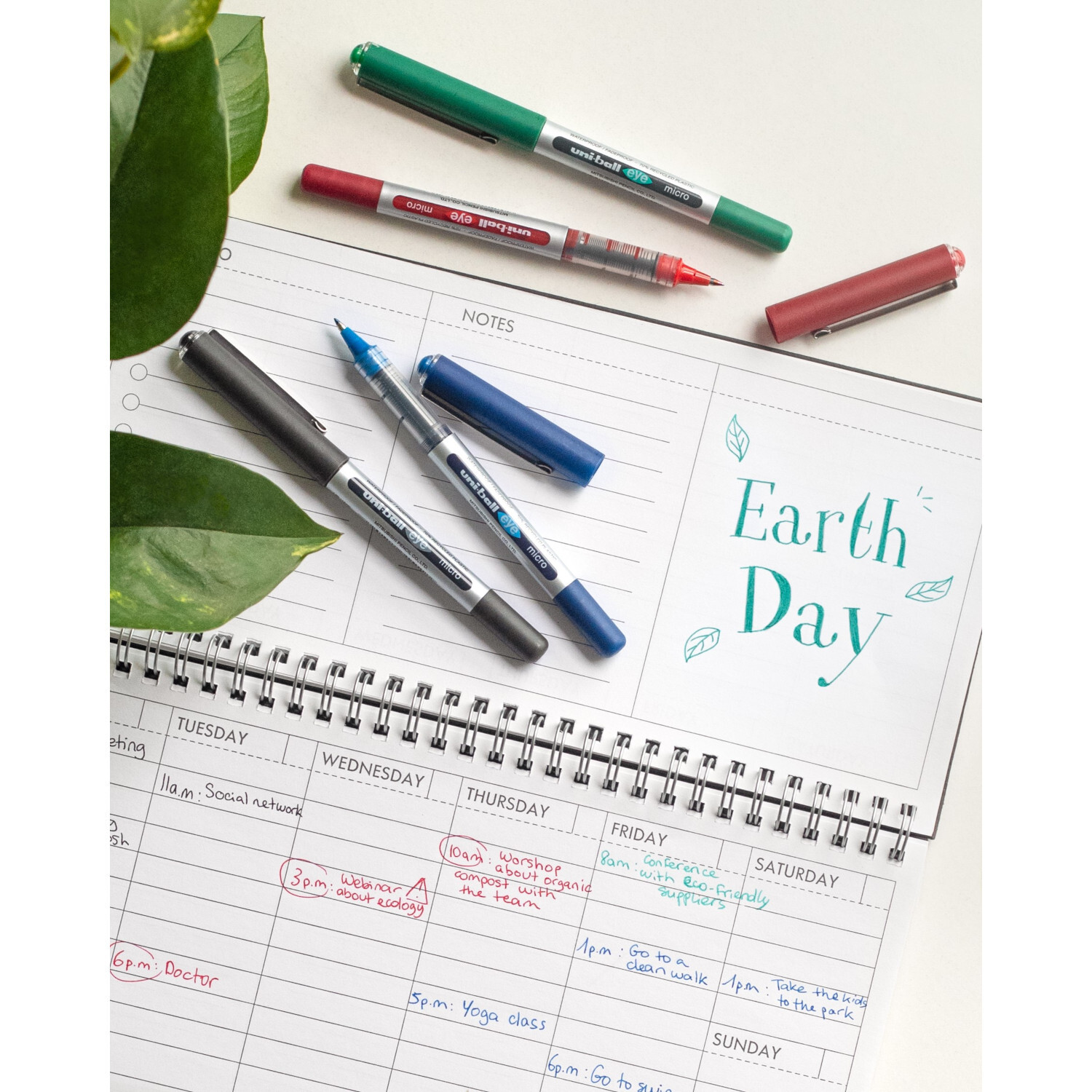 Tintenroller uni-ball Eye UB-150E auf einem Kalender mit Notizen und Earth Day-Schriftzug. Verschiedene Farben.