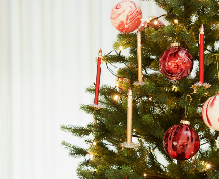 Ein Tannenbaum mit unterschiedlichen roten Christbaumkugeln und Glaskerzen. Fotosetting weißer Hintergrund und Tannenbaum.