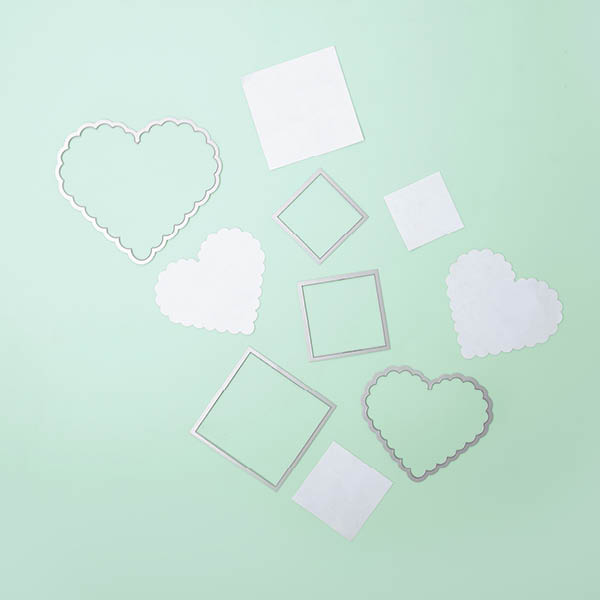 Framelits in Quadratformat und Herzform mit bereits ausgestanztem Papier in diesen Formen. Flatlay von Produkten.